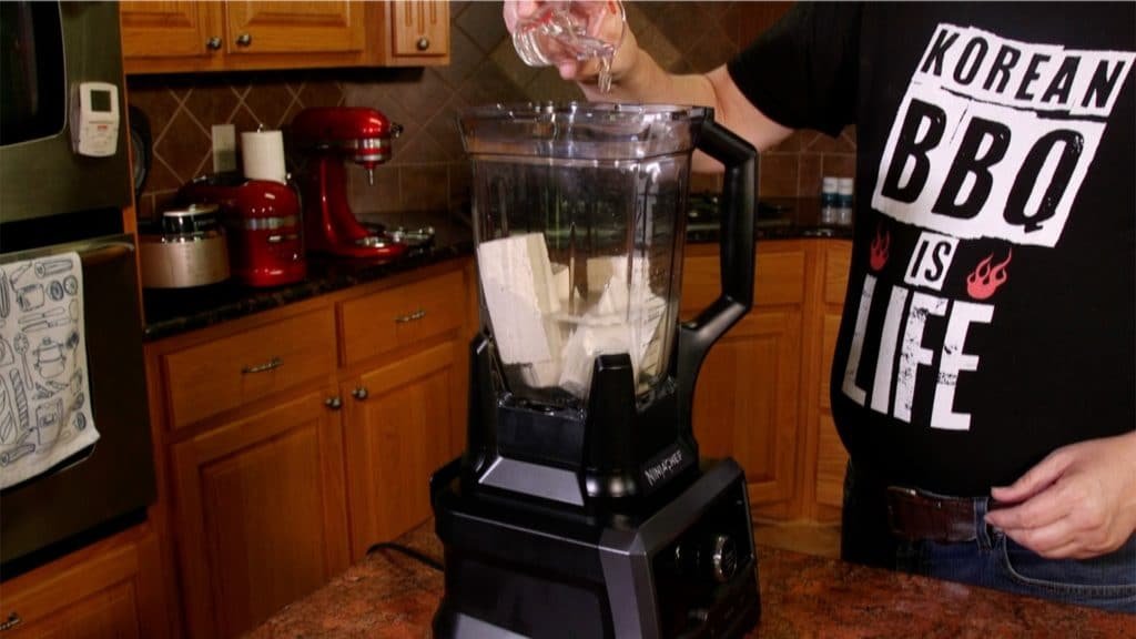 A blender with tofu and water prior to mixing 