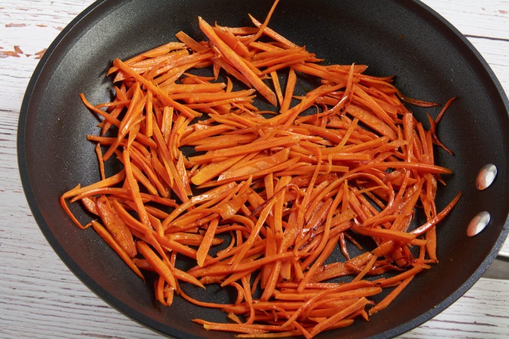 Cooked julienned carrots in a pan