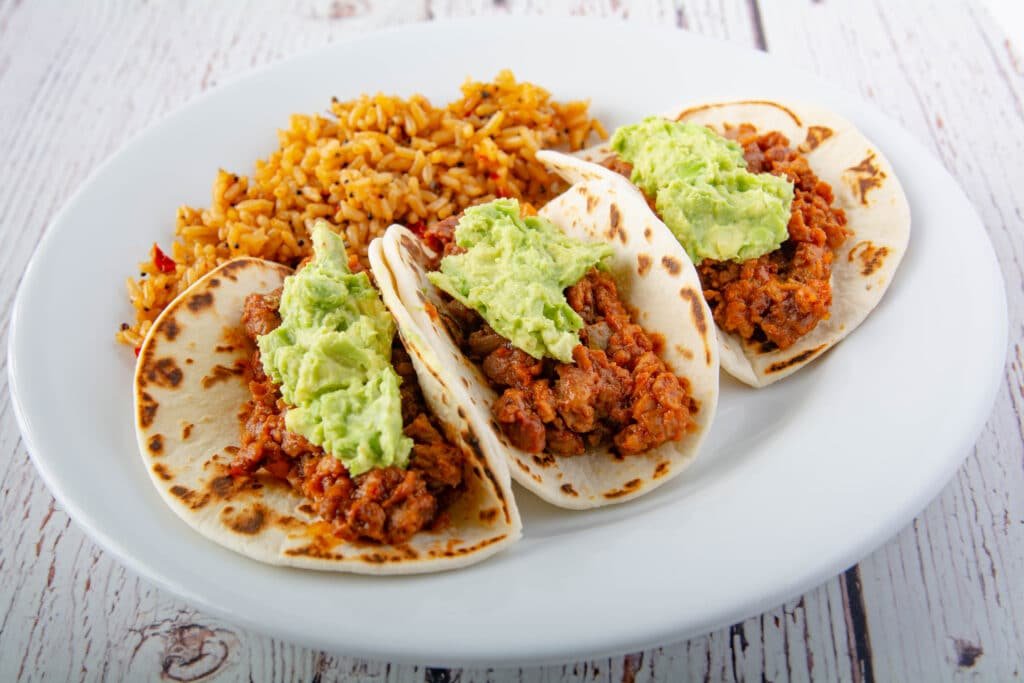 Three tacos with rice on a plate. 