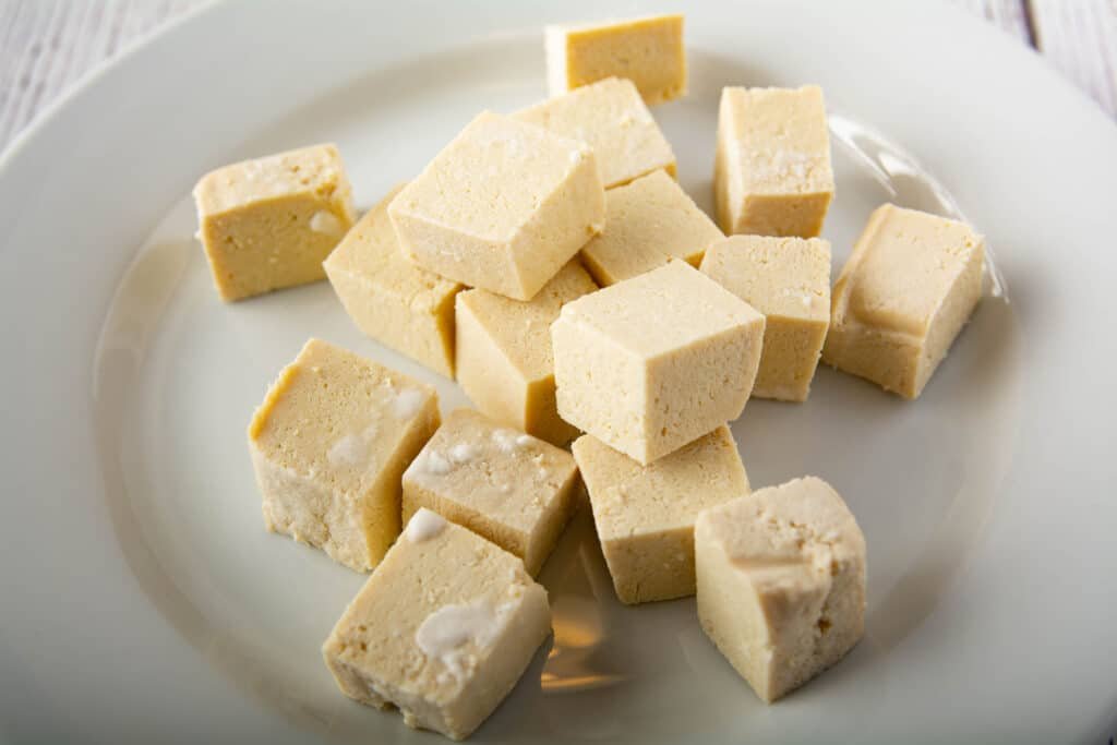 Raw cubed tofu coated with cornstarch on a plate 