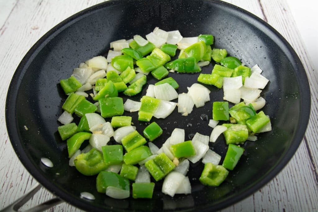 Cooked garlic, onion and green bell pepper in a pan. 