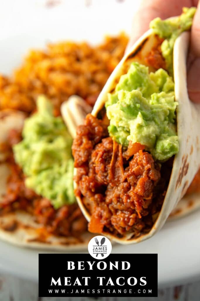 Closeup of a taco with guacamole, more tacos in the background. This is a pin for pinterest 
