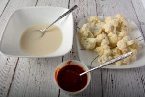 Bowl with the batter, prepared cauliflower and a bowl of sauce.