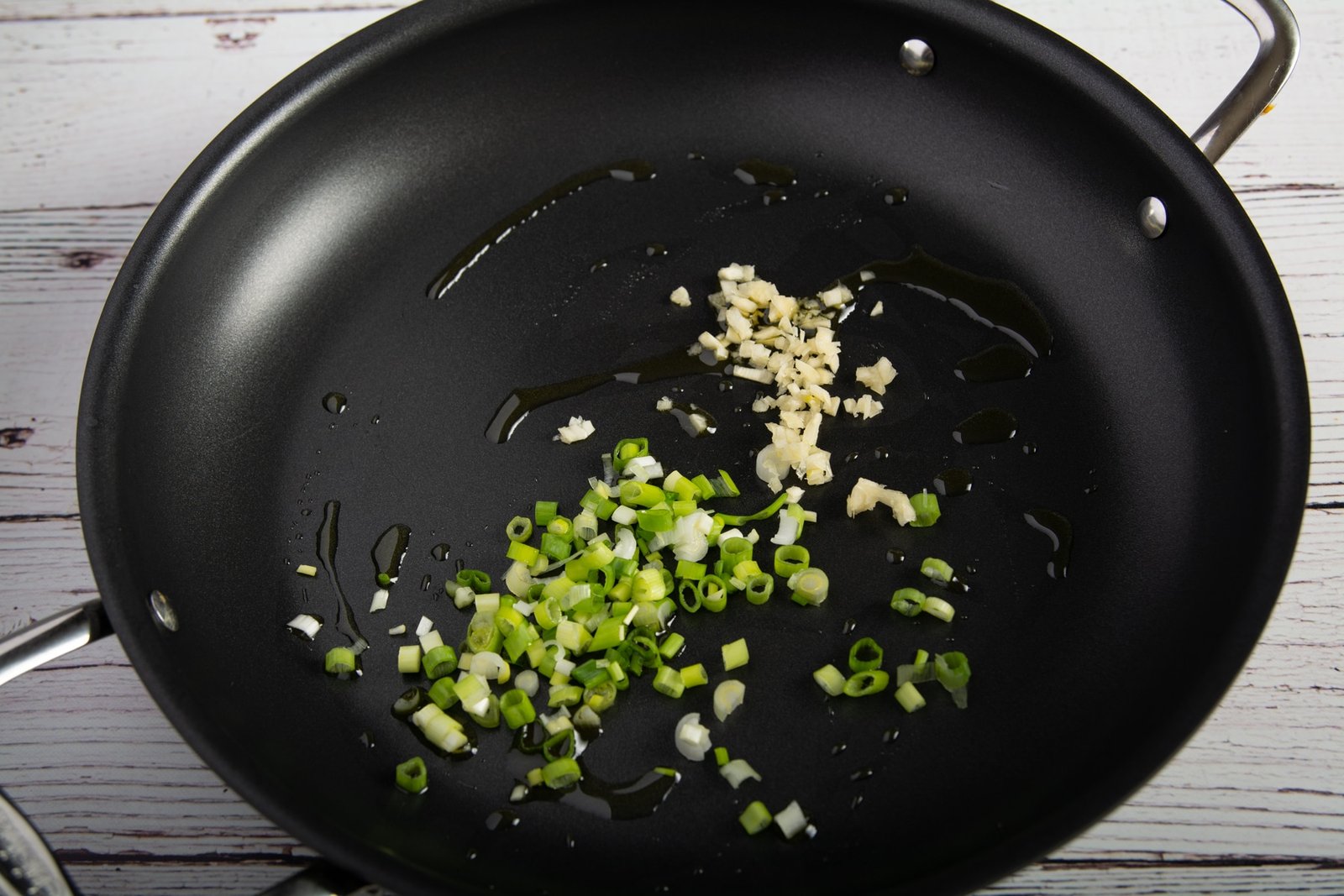 A pan with oil, garlic and green onion