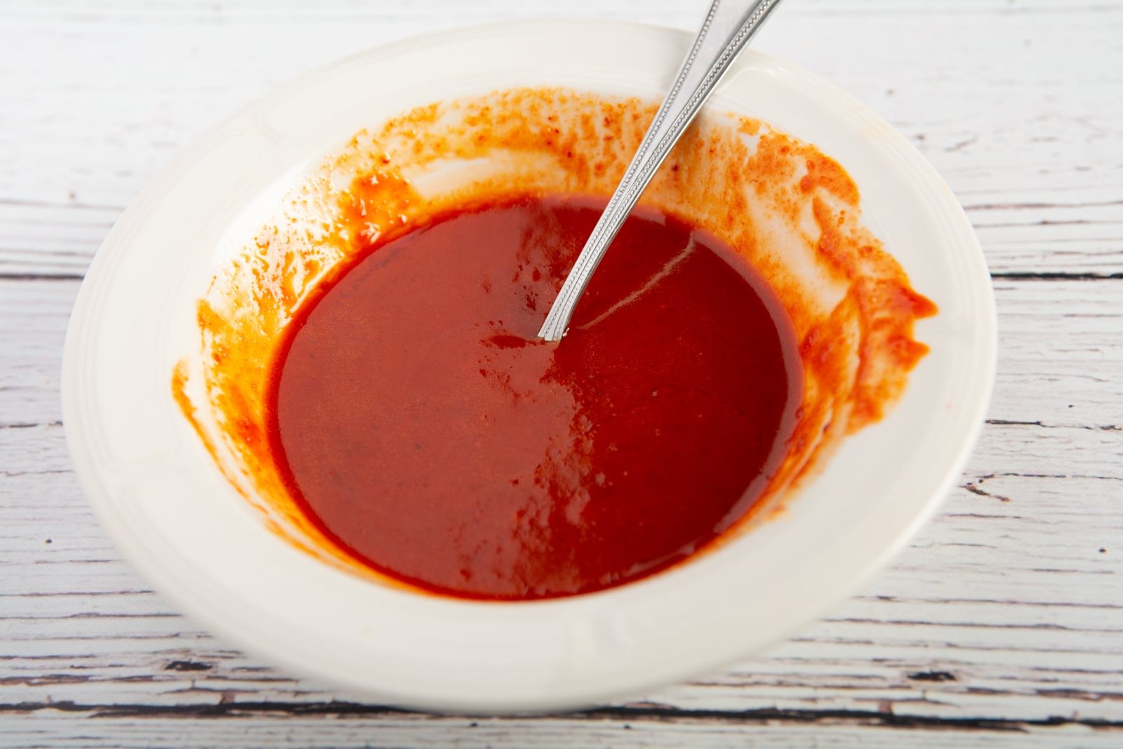 A bowl of spicy sauce with a spoon
