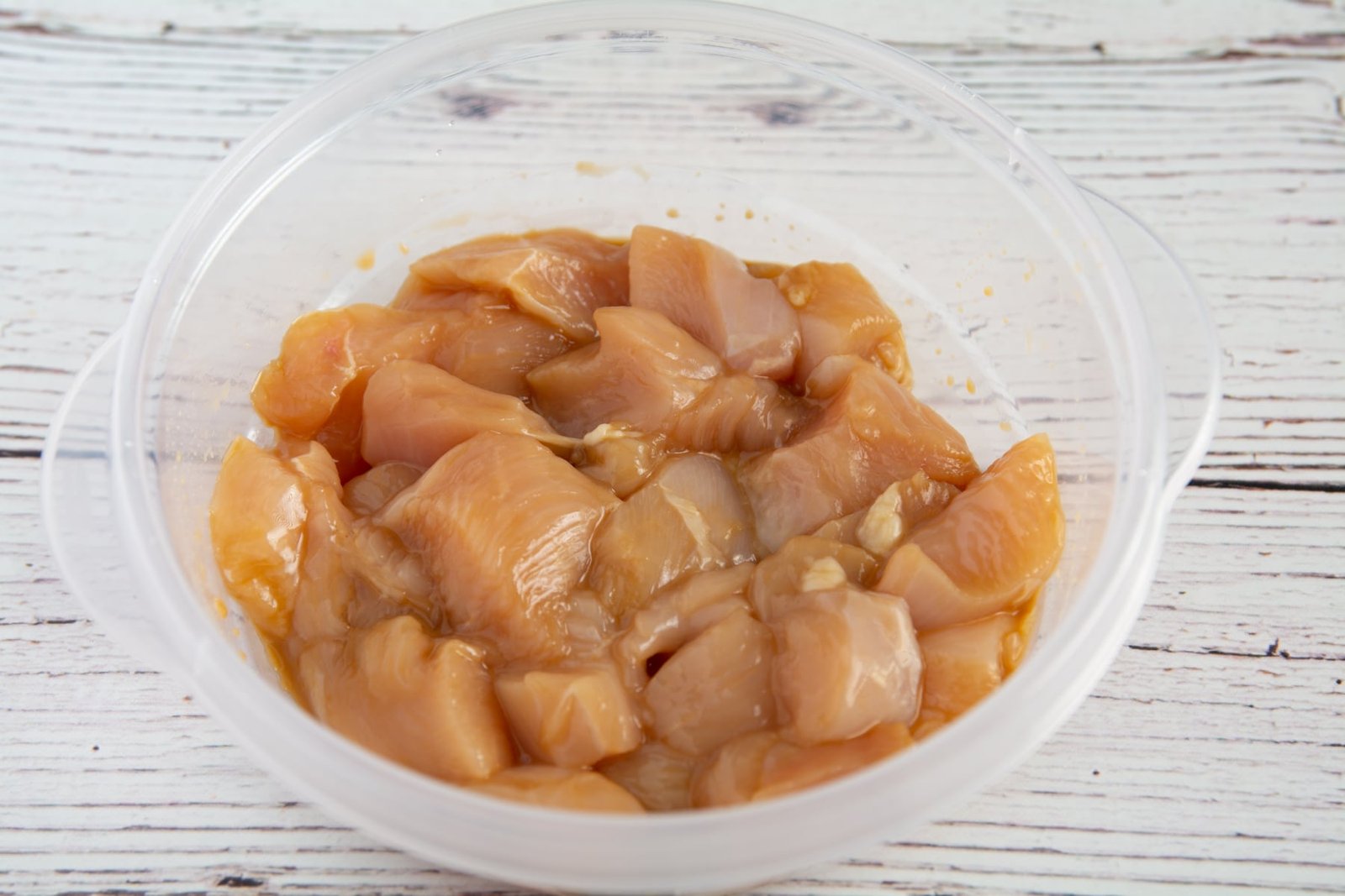 Raw chicken marinating in a bowl