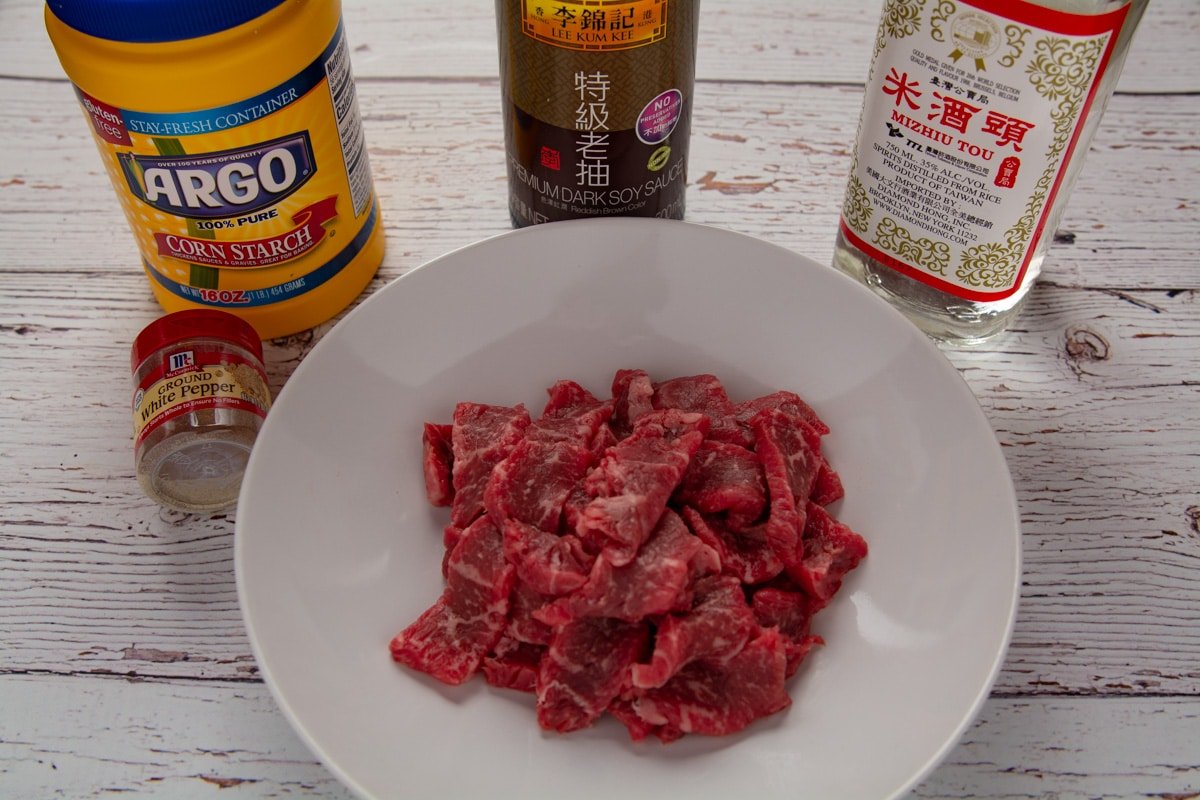 Raw slices of steak in a bold surrounded by marinade ingredients