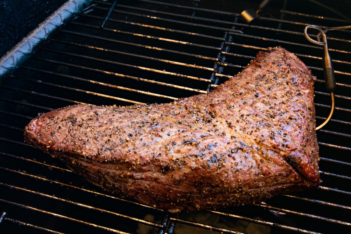 Half cooked tri tip on a grill with a thermometer