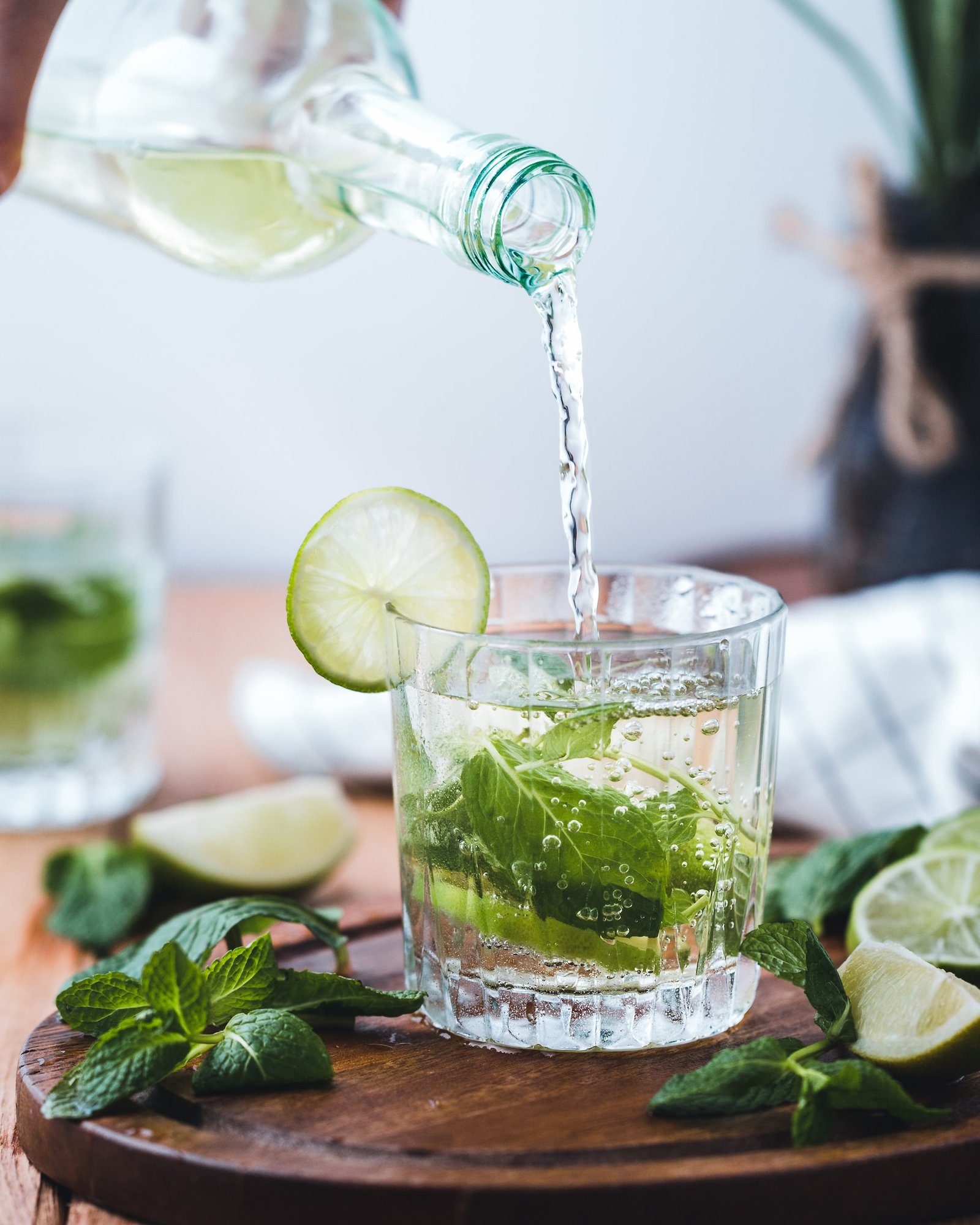 Poring water into a glass with mint and lime