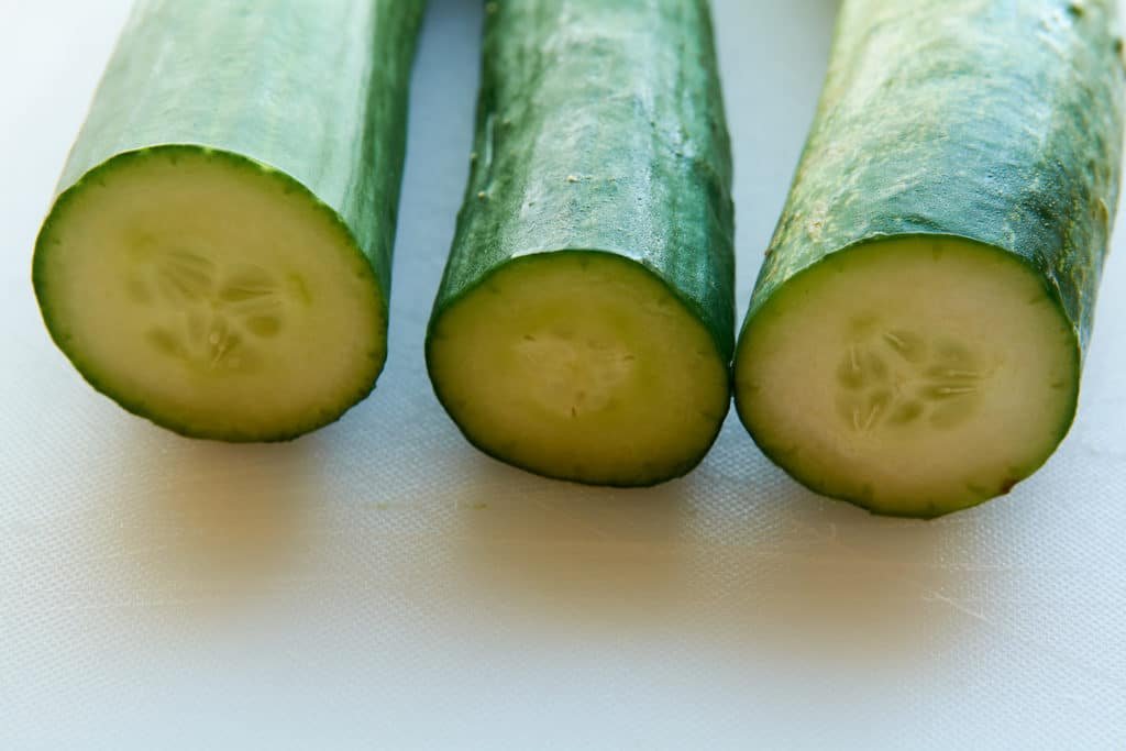 Three different types of cucumbers that have been cut. This show to difference of how they look inside 