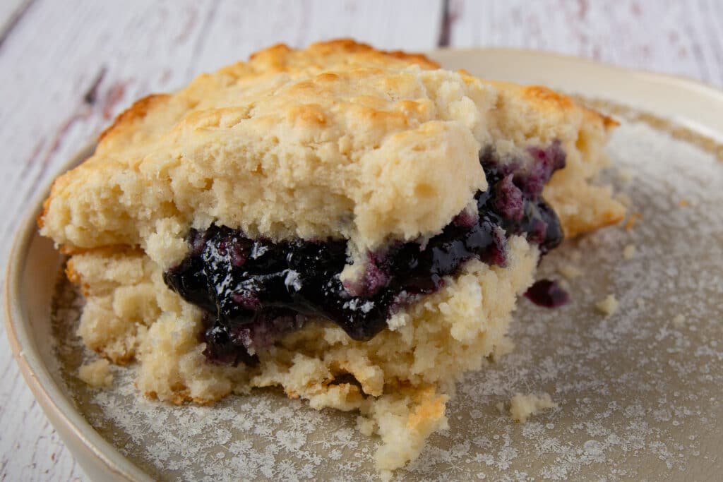 Vegan biscuit with blackberry jelly on a plate.