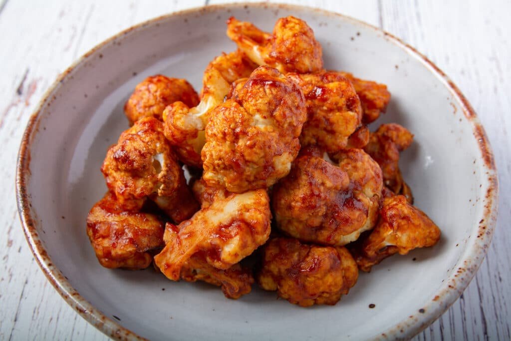 Oven baked cauliflower wings in a spicy Korean sauce in a bowl