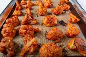 Oven baked cauliflower wings in a spicy Korean sauce on a baking pan fresh out of the oven