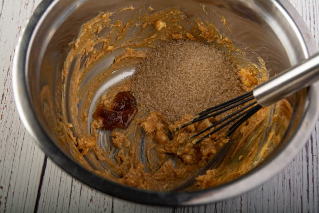 Metal mixing bowl with, butter, peanut butter, sugar and honey with a whisk
