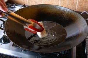 Battered tofu being placed into hot oil for frying