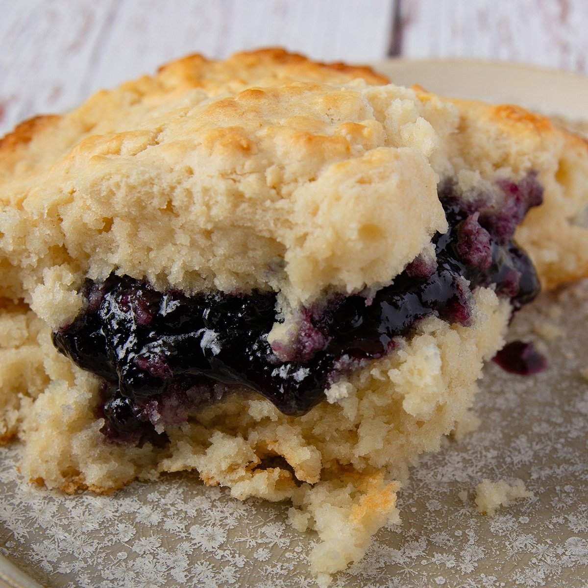 Vegan biscuit with blackberry jelly on a plate.