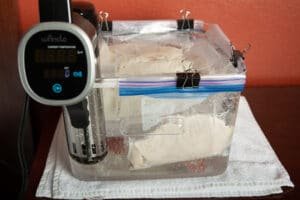Bags of chicken breast in a tank with a sous vide machine.