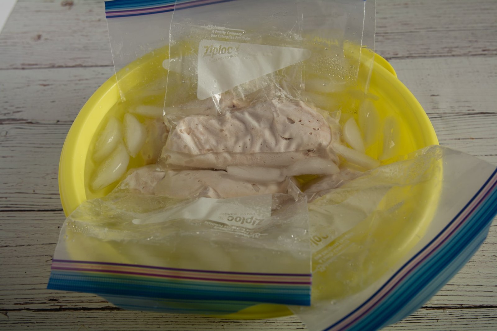 Bags of chicken breast in a bowl of ice water