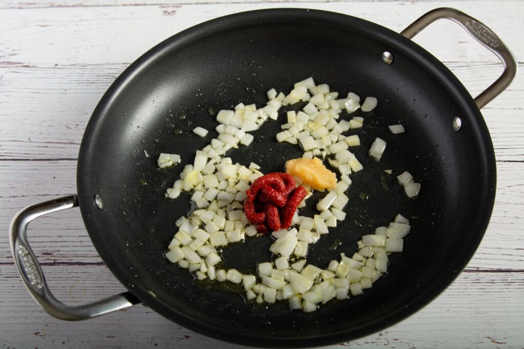 Cooked onions with raw garlic and tomato paste in a pan