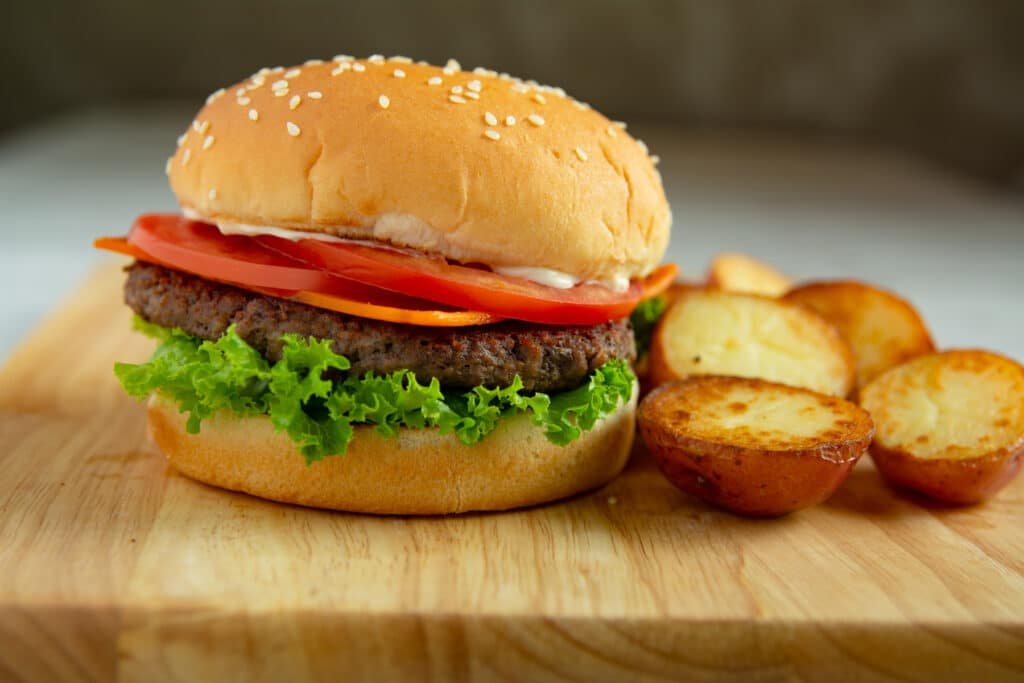 Burger and fried potatoes on a cutting board