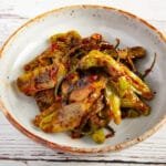 Blistered peppers with a spicy sauce in a bowl.