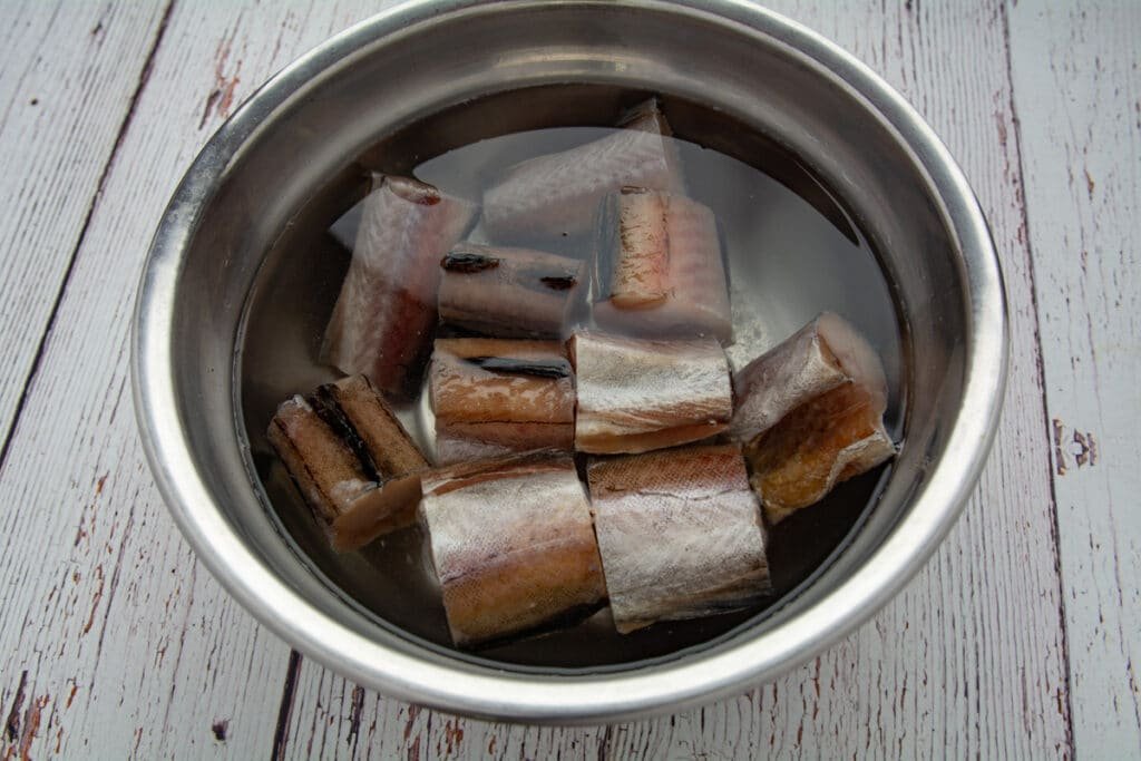 Frozen fish in a bowl soaking in salt water.