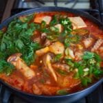 Spicy fish stew cooking on a stove.