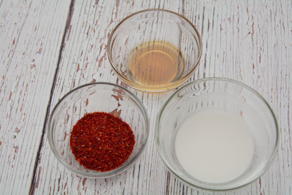 Bowls with sesame oil, red pepper flakes and rice flower mixed with water.