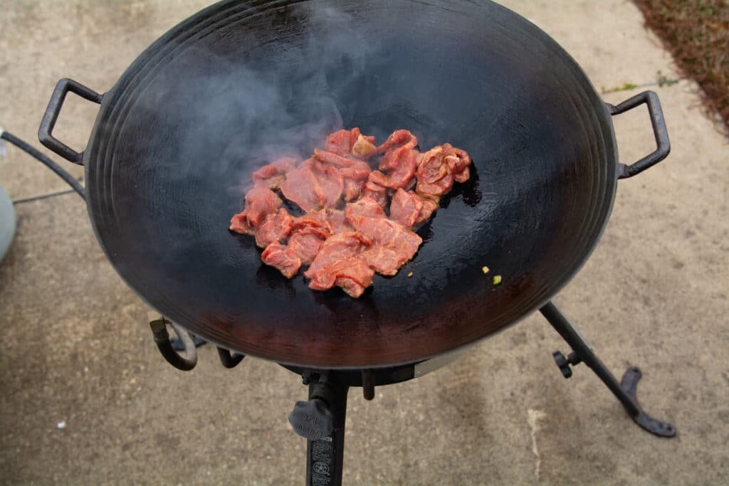 Strips of steak just after adding to a wok.