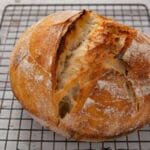 A loaf of sourdough bread cooling on a rack
