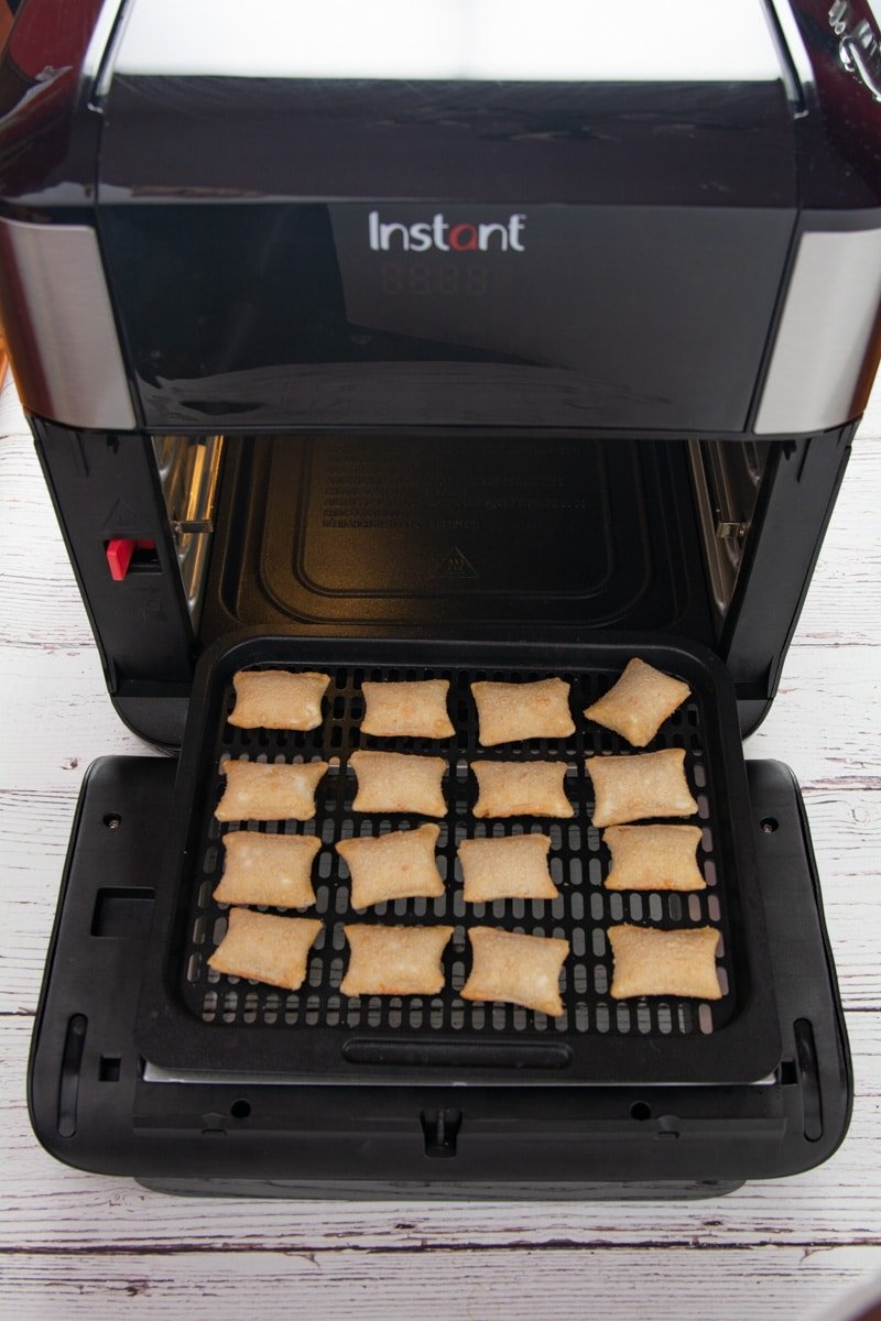 Pizza rolls on a cooking rack in front of the air fryer