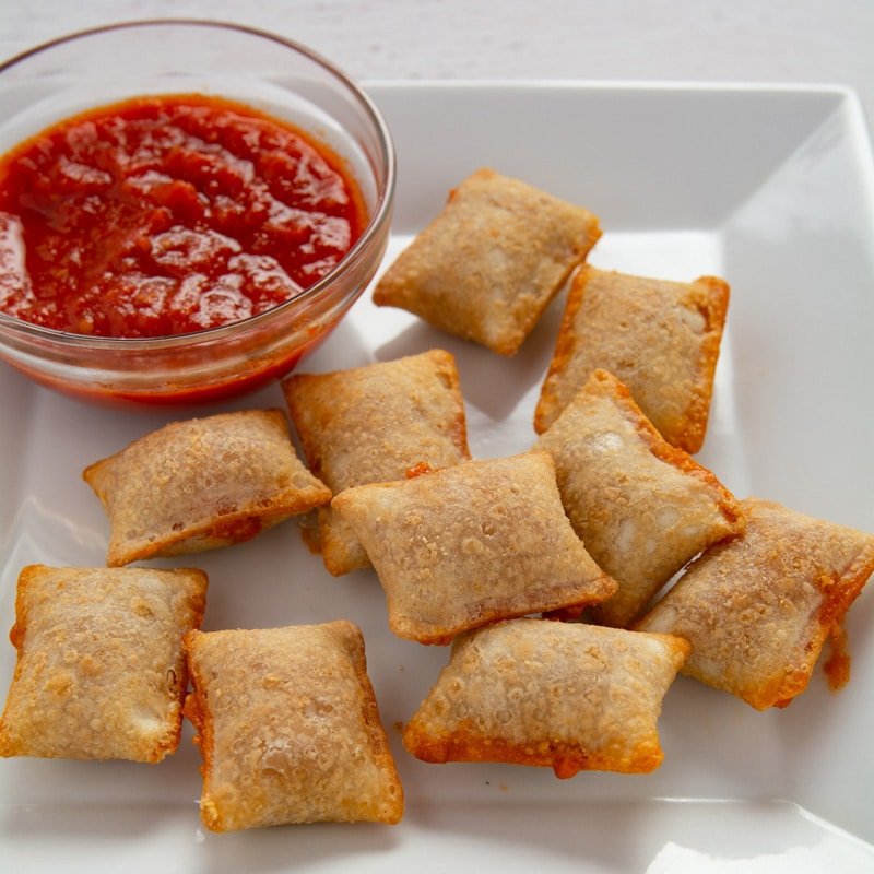 Air fried pizza rolls on a plate with a bowl of sauce.