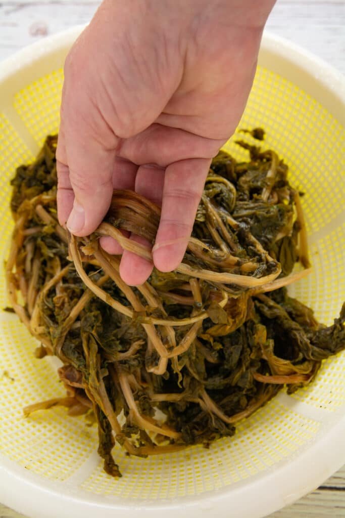 A hand peeling the dried radish stems