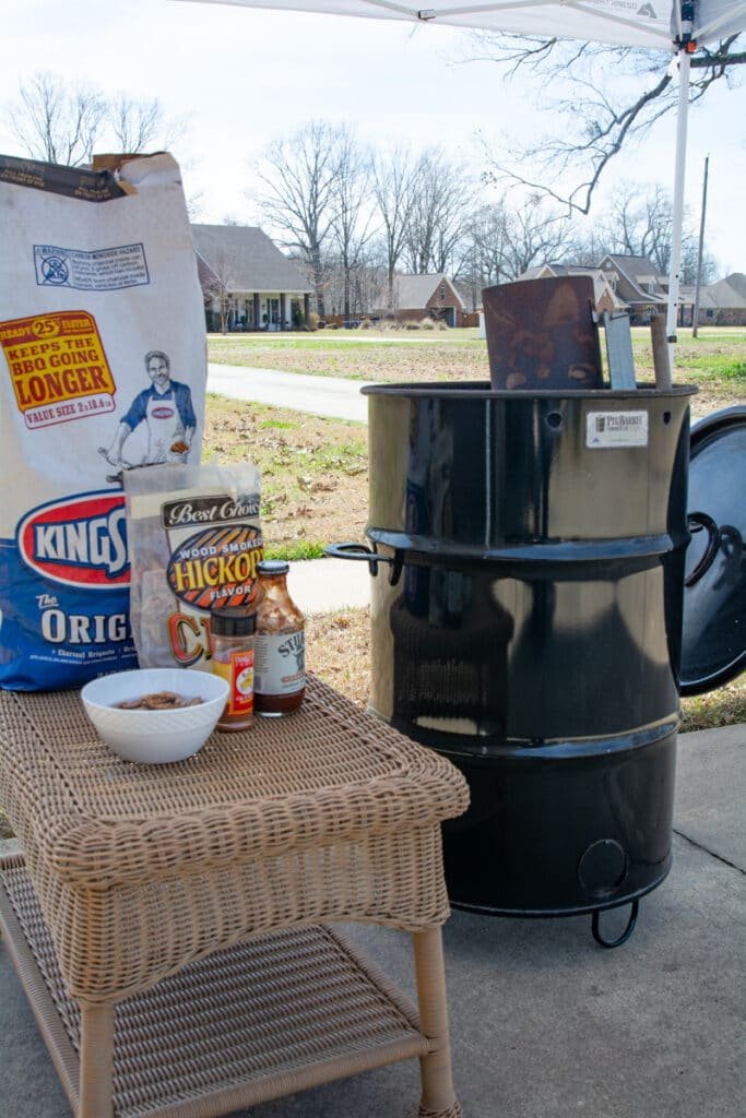 pit barrel cooker, charcoal, wood chips and a chimney starter being used to light the charcoal.