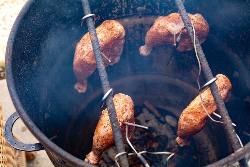 Chicken leg quarters cooking inside of a pit barrel cooker