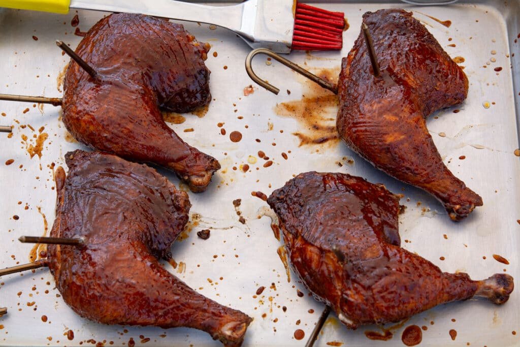 Chicken leg quarters with sauce on a pan with a brush