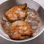 Cooked pork chops in a pan with oil