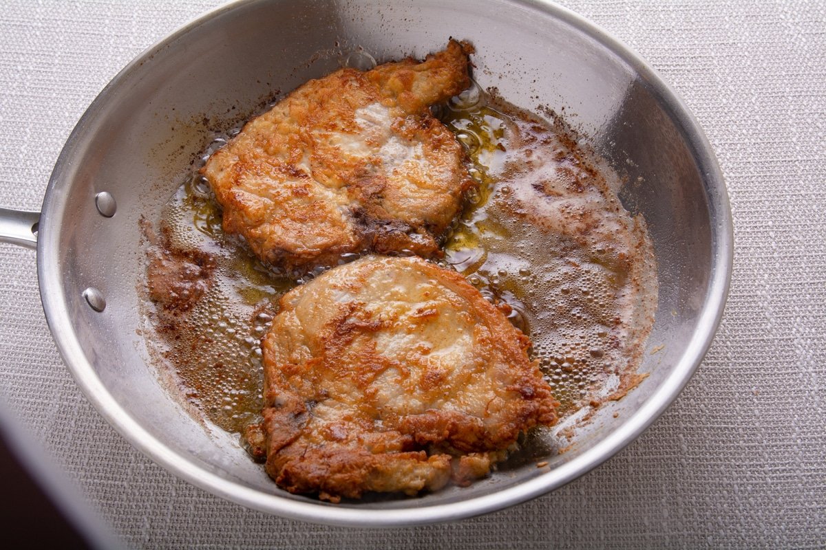 Cooked pork chops in a pan with oil