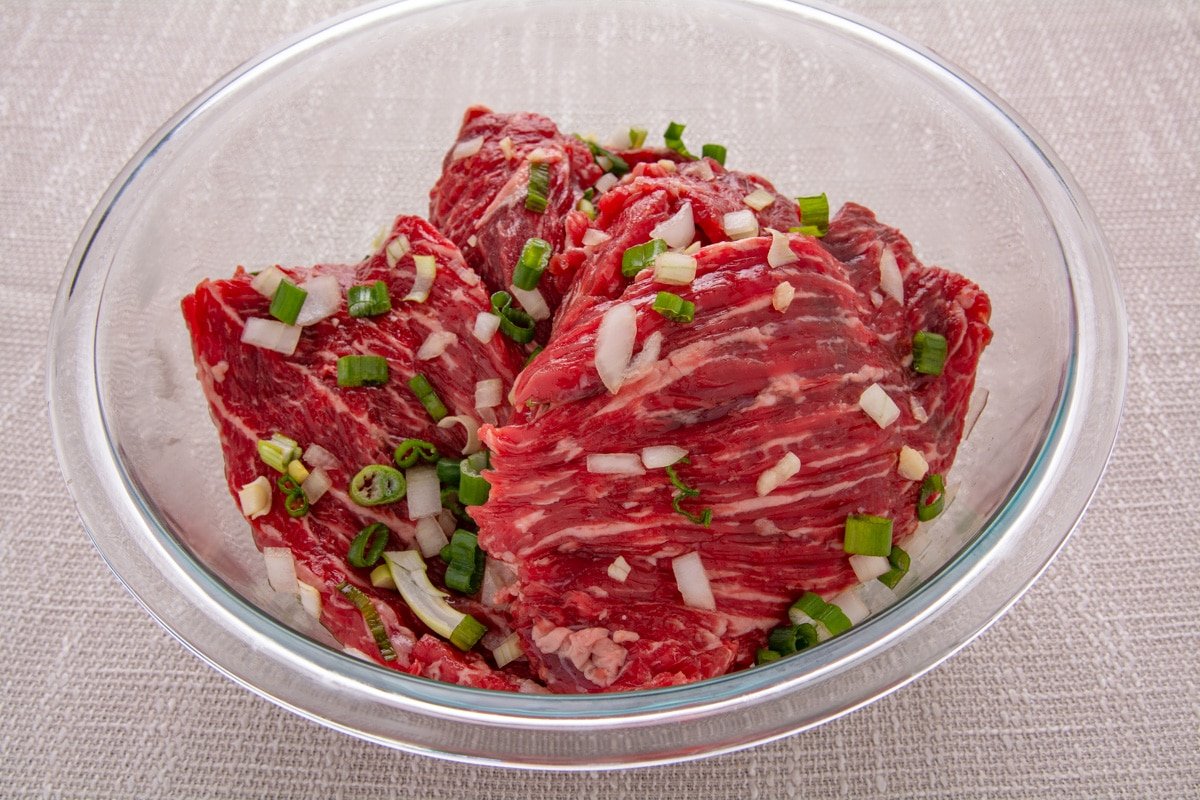 Seasoned beef marinating in a glass bowl
