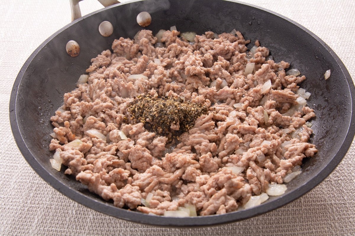 Partially cooked ground pork with spices in a pan