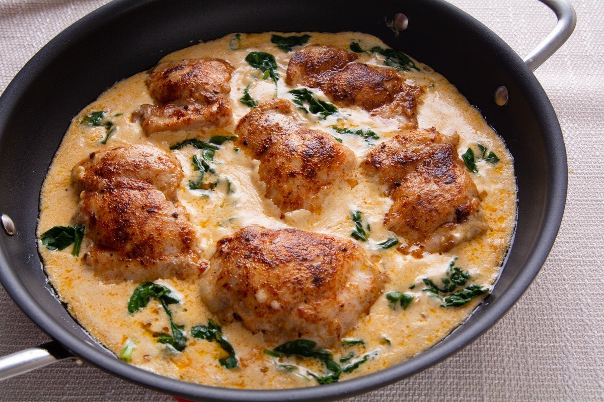 Cooked chicken thighs and cream sauce in a pan. 