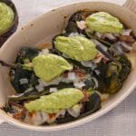 Cooked chili rellenos with green salsa in a pan