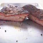 Cooked brisket cut showing the inside laying on a pan.