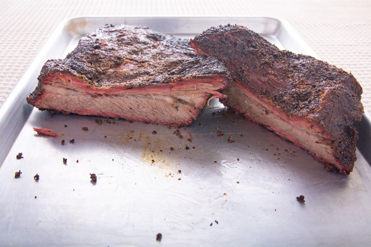 Cooked brisket cut showing the inside laying on a pan.