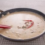 Pan of white gravy with a spoon.
