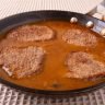Fried cube steaks in a pan of brown gravy