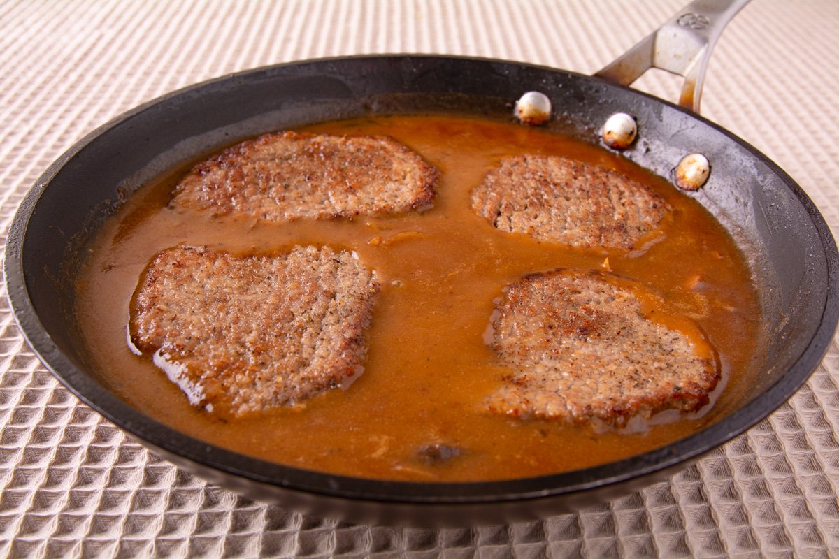 Fried cube steaks in a pan of brown gravy