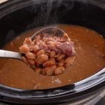 A ladele scooping up finished pinto beans from a crockpot.