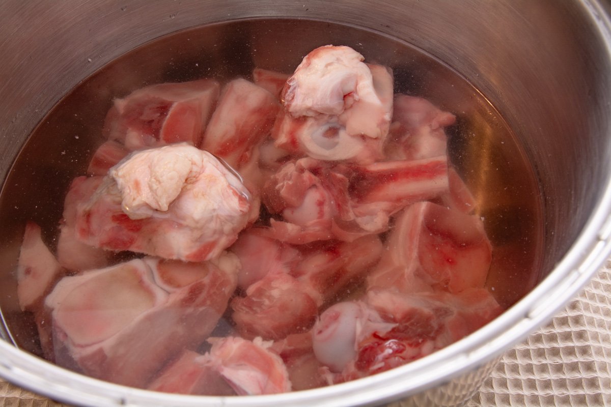 Pork bones soaking in a pot of water