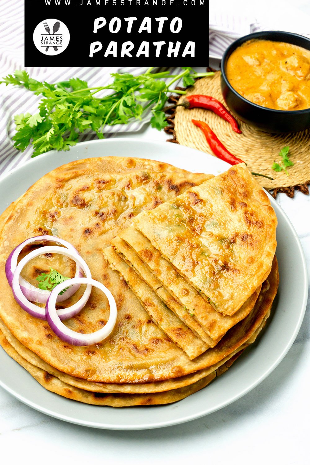 Cooked potato stuffed parathas on a plate with a bowl of curry in the background. This is a pin for Pinterest.